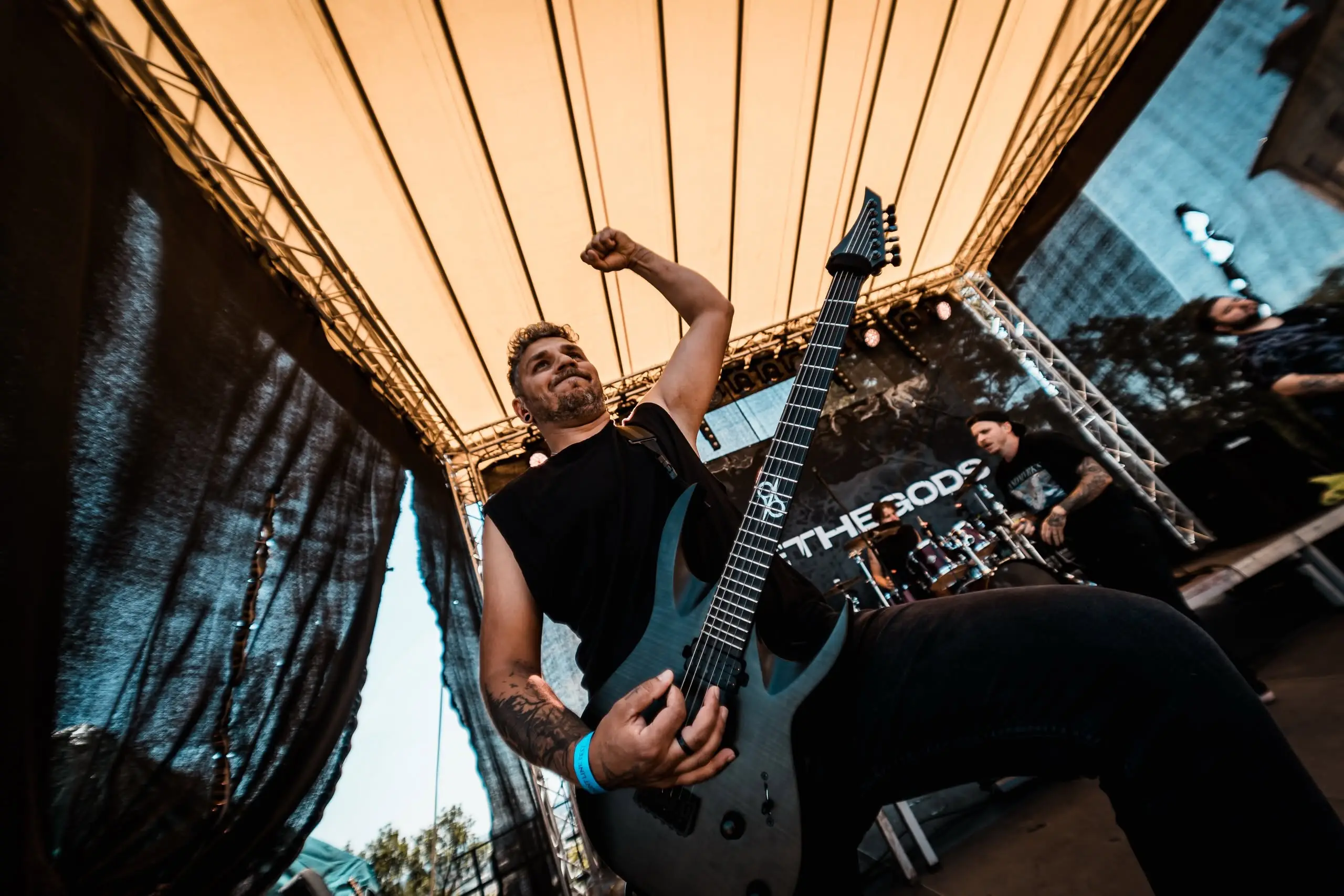 Guitarist raising his fist under the open-air stage roof, Front Line Fest 2026