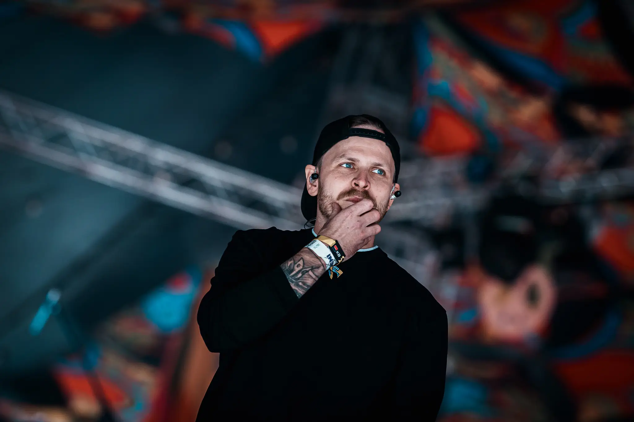 Vocalist in a cap, hand on his chin, looking into the crowd